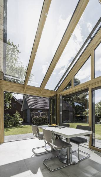 L'Ouverture Française a installé des portes coulissantes pliantes d’un côté et l’autre des portes coulissantes minimalistes en bois à l'intérieur avec aluminium à l'extérieur de la marque Solarlux sur une véranda.