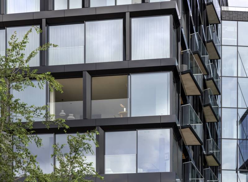 Cette baie coulissante en aluminium mesure 245 cm par 225 cm et entoure la façade avec des garde-corps en verre épais.